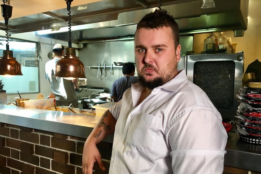 Chef Josh Arthurs standing in front of the kitchen at his restaurant.
