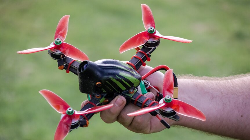 A close up of a man's hand holding a racing drone.