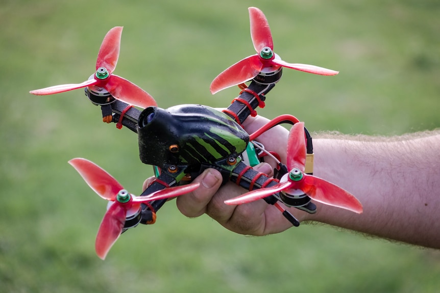 A close up of a man's hand holding a racing drone.