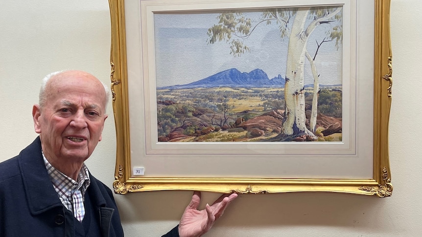 A man stands beneath a framed watercolour painting