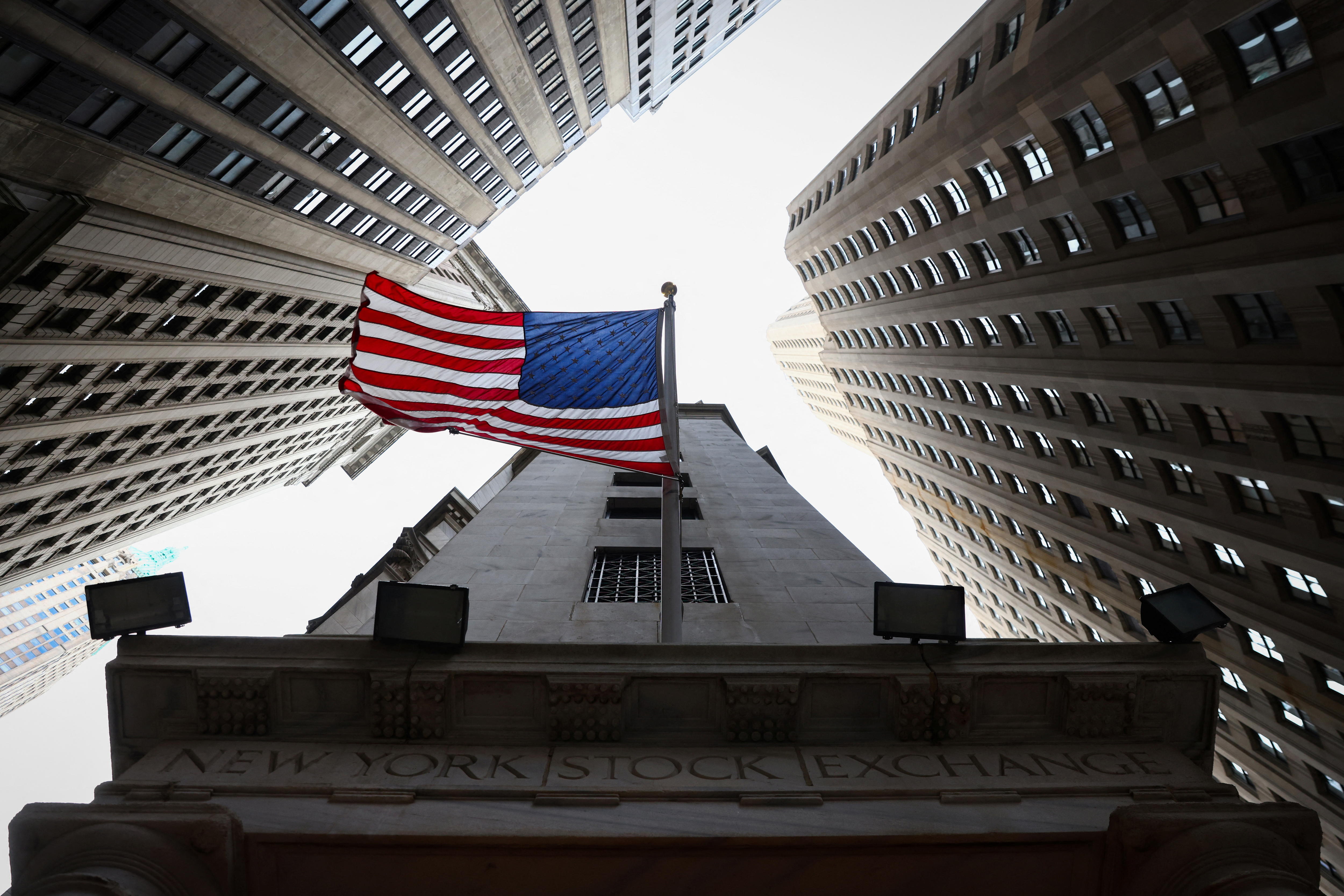 An American flag that flies outside a building surrounded by skyscrapers.