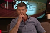 Jonathan Brown holds his hand up to his mouth as he sits on a couch presenting the AFL 360 TV show.