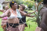 Women dancing in Vanuatu, with one wearing a bra with a flower in her hair.