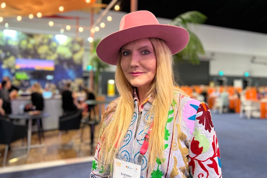 Una mujer con un sombrero rosa y una chaqueta multicolor.