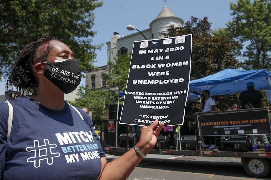 A woman holds a sign saying 1 in 6 black women are unemployed.