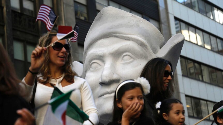 Two women and children ride a float with a statue of a large white head.