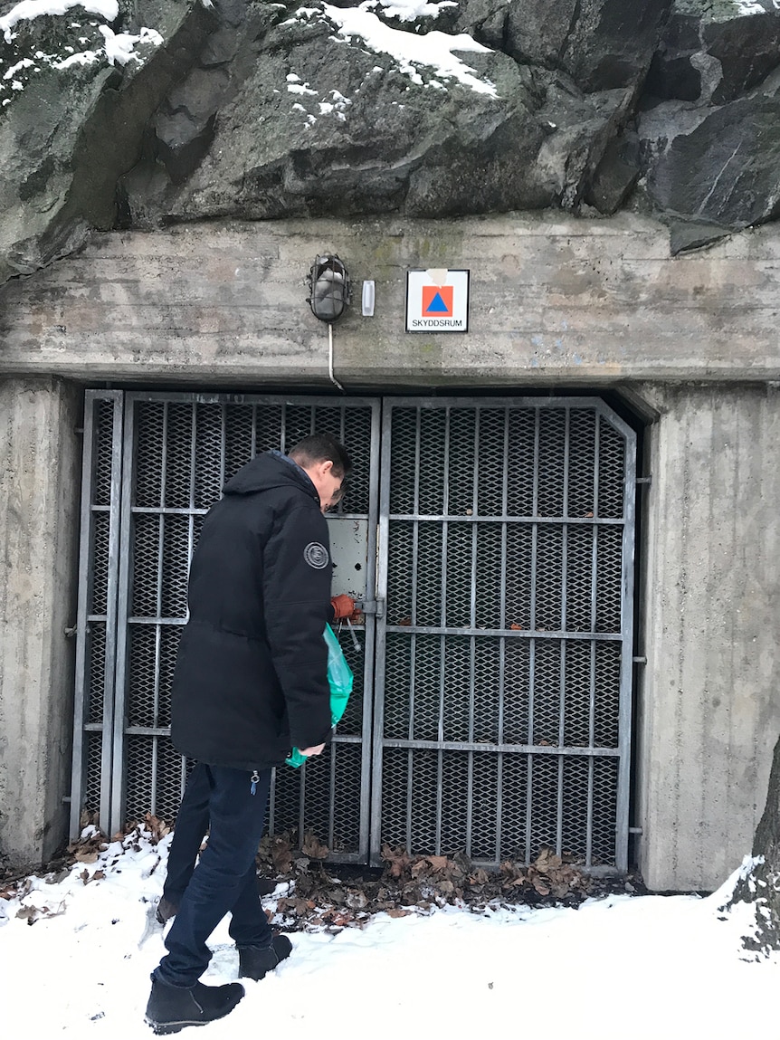 Man  stands in the snow outside a shelter in Sweden.