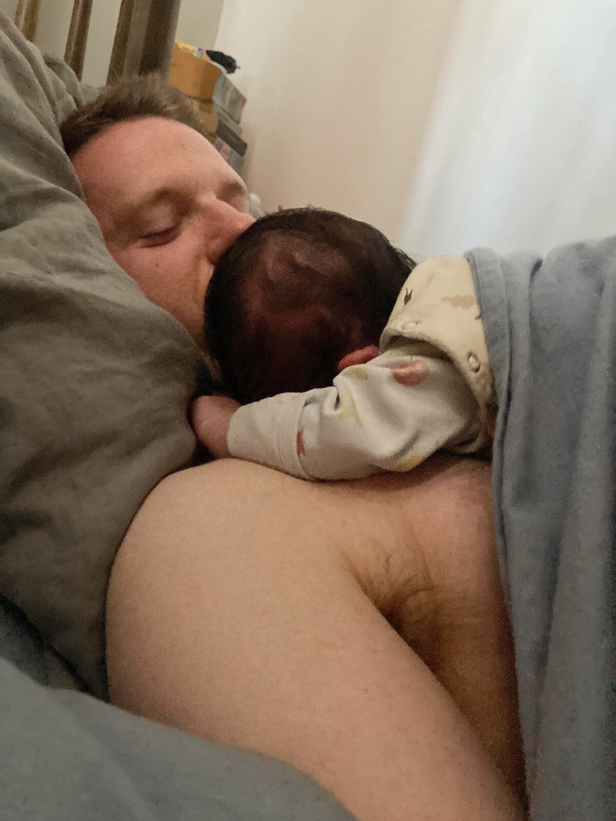 Alex McKinnon lies against the pillow in his bed with his baby daughter on his chest. 