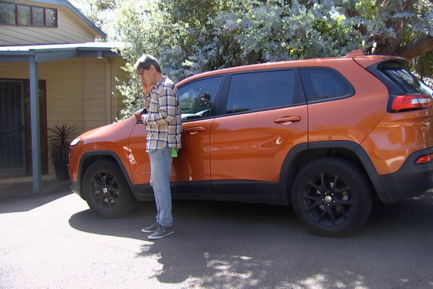Jorge Gonez se para frente a su auto, comprado con financiamiento de Latitude.