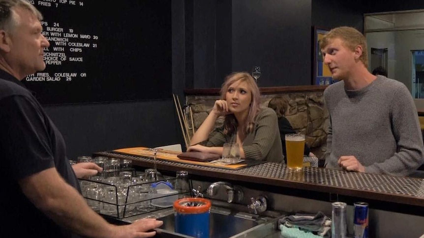 Two young people in an Australian pub talk to an older publican