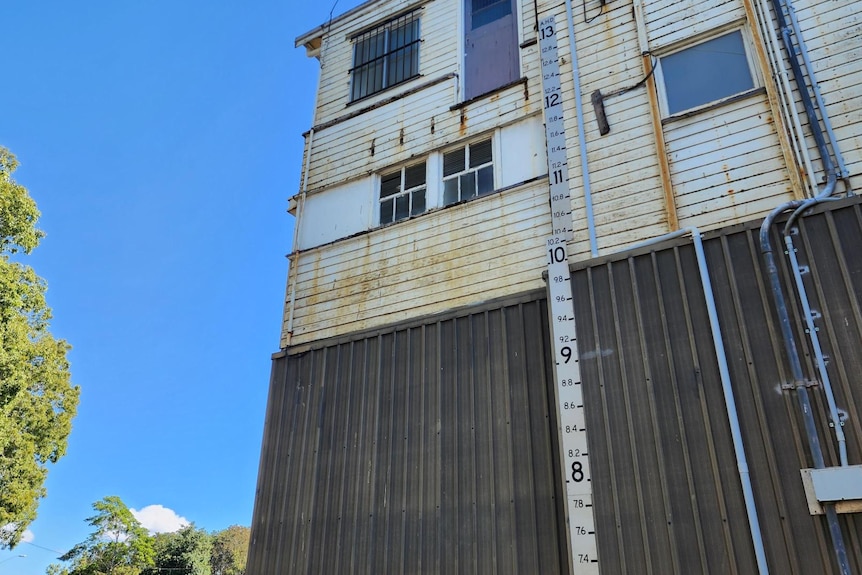 metal flood marker with numbers visible attached to an exterior wall of a three storey building