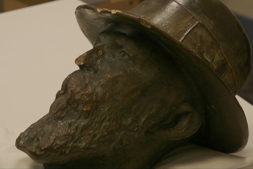 A decapitated head of a bronze statue sitting on a desk.