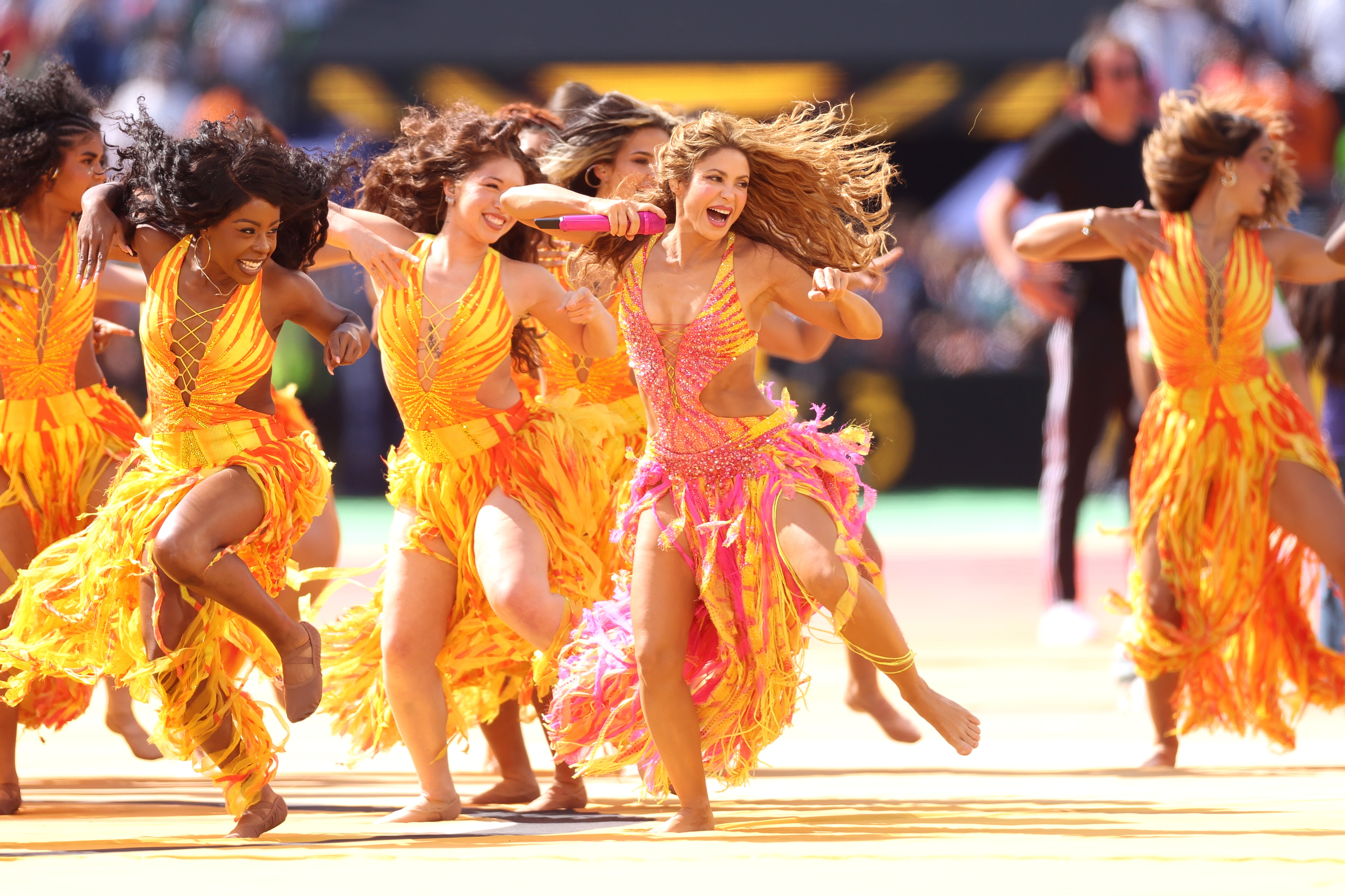 Women in orange costumes, dancing.