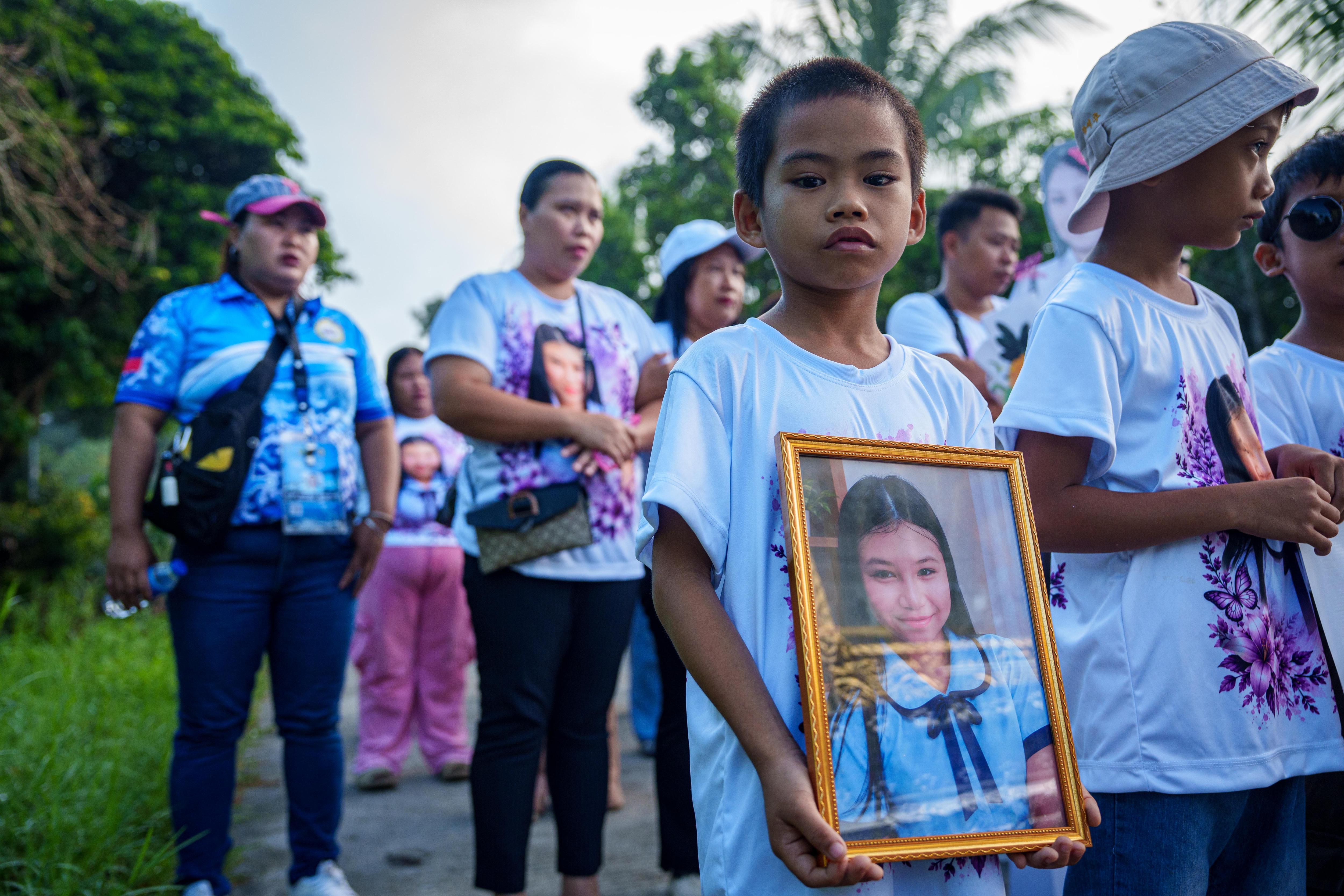 A young Filipino boy holds a framed photo of a schoolgirl.