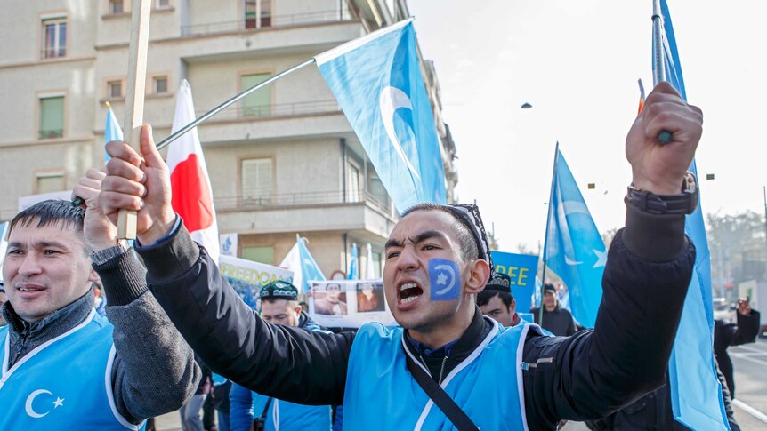 Uyghurs people demonstrate against China near the United Nations in Geneva. They are holding blue East Turkestan flags.