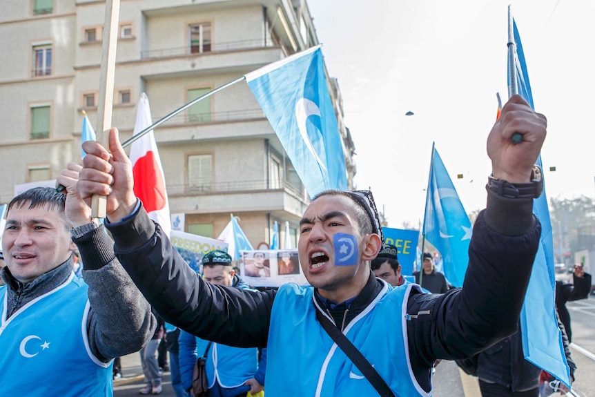 Uyghurs people demonstrate against China near the United Nations in Geneva. They are holding blue East Turkestan flags.