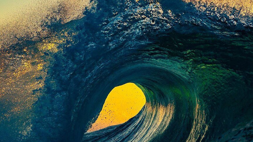 The sun is framed perfectly by a barrelling wave.