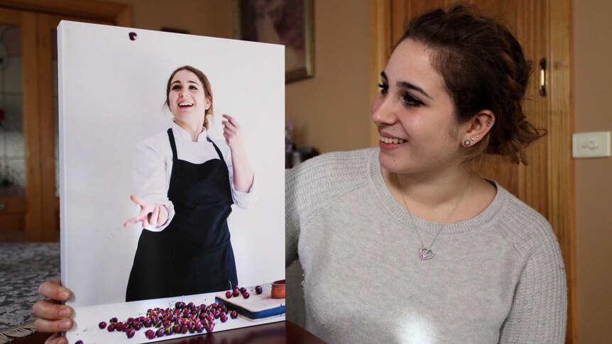 Former BurchPurchese worker Angelica  looks at a photo of herself working as a pastry chef.