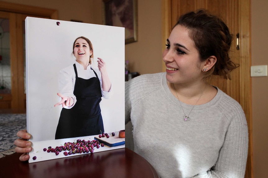 Former BurchPurchese worker Angelica  looks at a photo of herself working as a pastry chef.