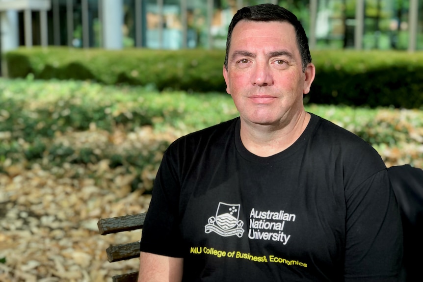 Man wearing a black t-shirt that has Australian National University written on it.