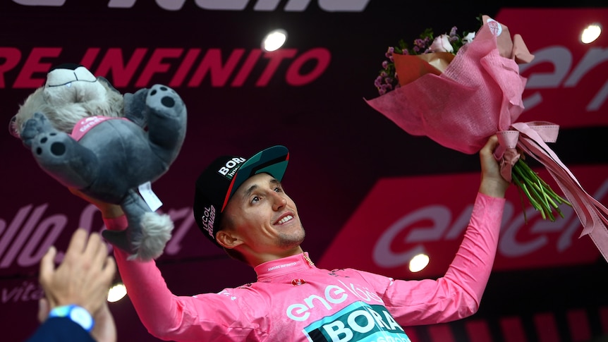 Australian cyclist Jai Hindley celebrates on the podium wearing the leader's pink jersey (Maglia Rosa).
