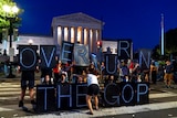 Protesters gather with a sign reading "overturn the GOP".