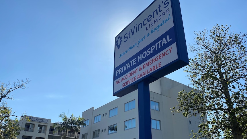 A hospital sign saying St Vincent's private hospital, white building behind, blue sky.