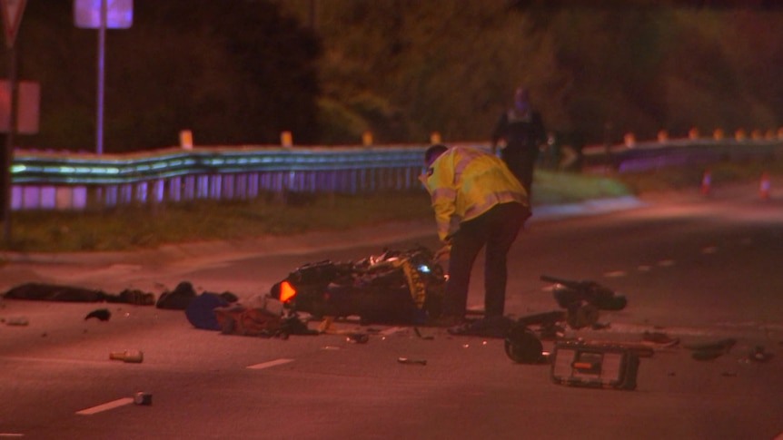 A police officer inspects a damaged motorcycle.