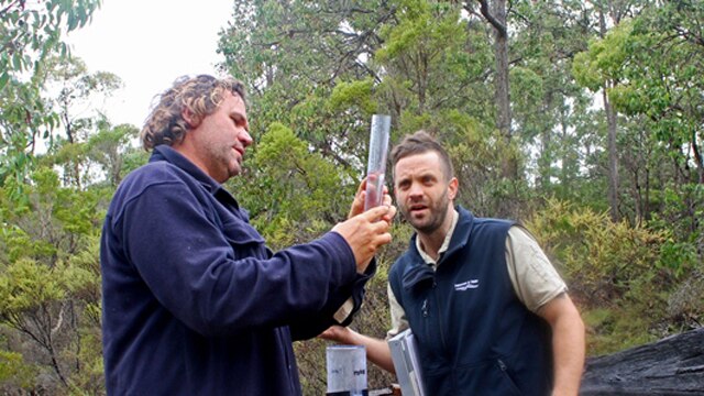 Two men with water measuring equipment in the bush