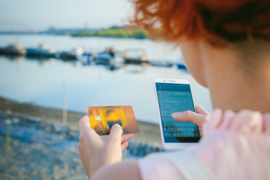 A woman holding a mobile phone and a credit card.