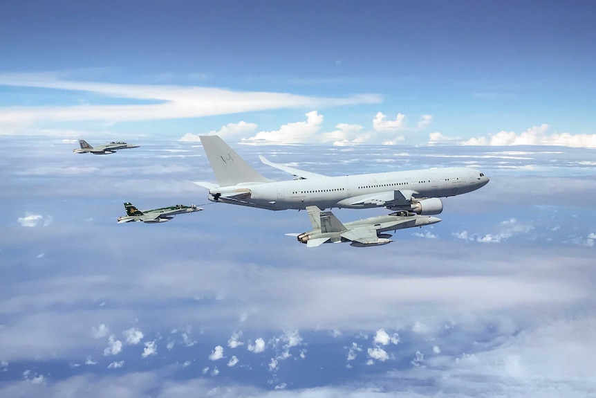 Large plane above clouds flying in front of three smaller plans