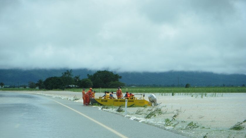 SES volunteers in floodboat alongside flooded Bruce Highway near Ingham in north Qld.