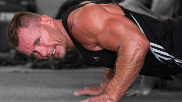 A man grimaces while doing push-ups