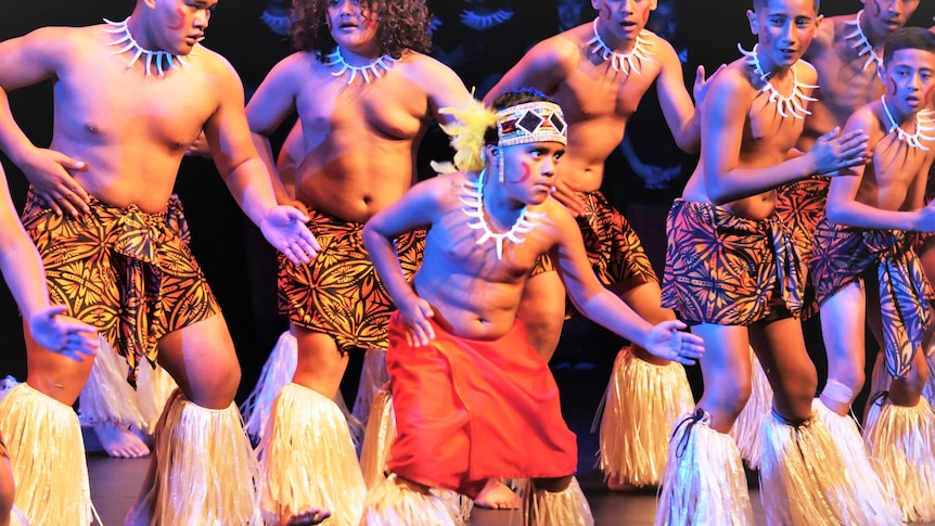 Young men in colourful Samoan clothing performing their fa'ataupati, or slap dance, a young boy out front