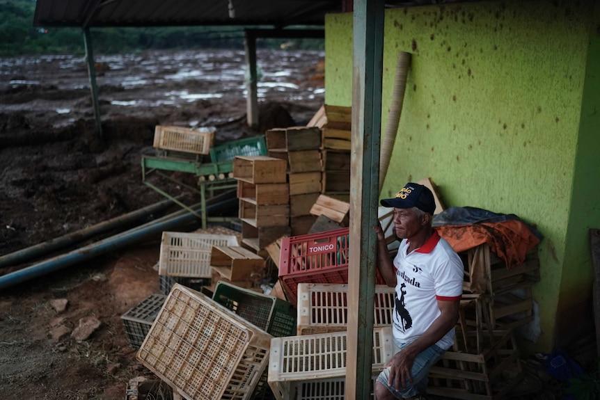 A man stands next to what remains of a market after a dam collapse.