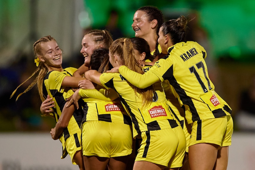 Soccer players wearing yellow and black celebrate after scoring a goal