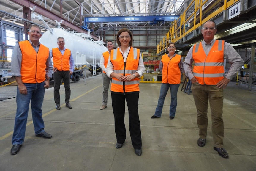Deb Frecklington and other LNP candidates wearing high visibility vests over their clothes in a factory or warehouse