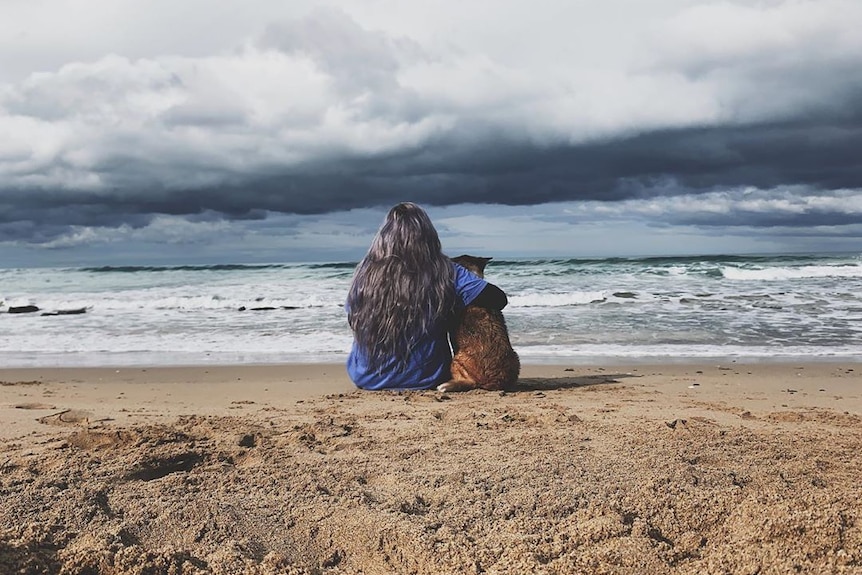 woman and dog at beach with back to camera