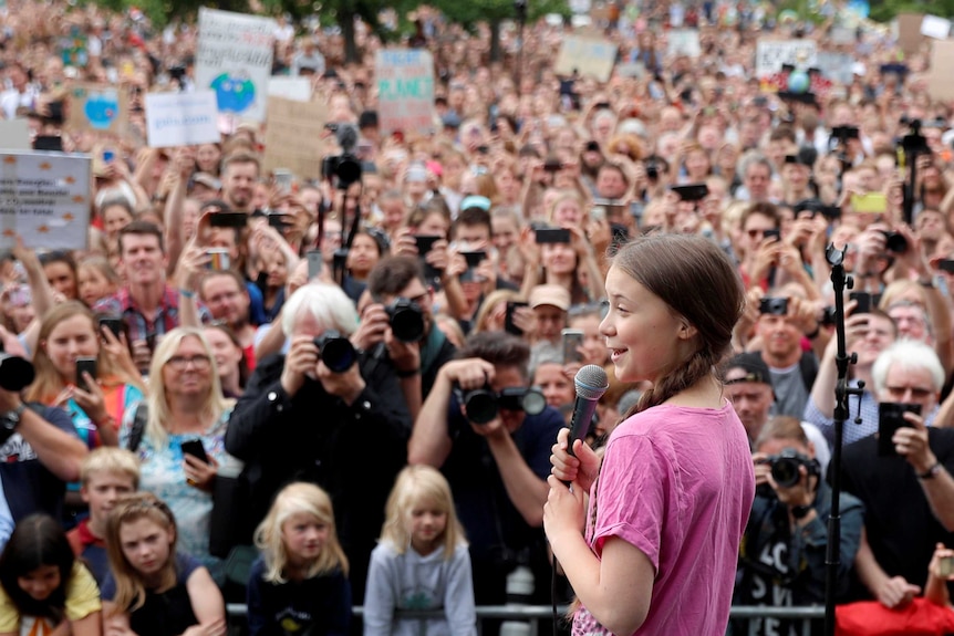 Greta Thunberg holds a microphone on stage as she speaks to a crowd