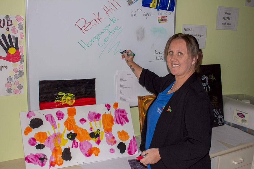 Aboriginal Youth and Family worker, Janice Millett, writes on a white board at the Peak Hill Homework Centre in central NSW