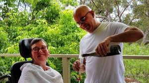 A man pouring wine for a woman in a wheelchair.