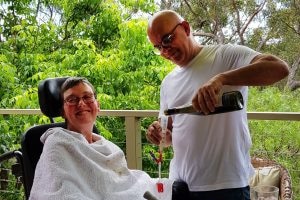 A man pouring wine for a woman in a wheelchair.