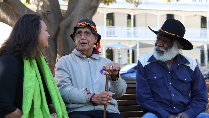 WA Indigenous leaders Carol Innes, Ben Taylor and Glen Cooke sit on a park bench talking to eachother.