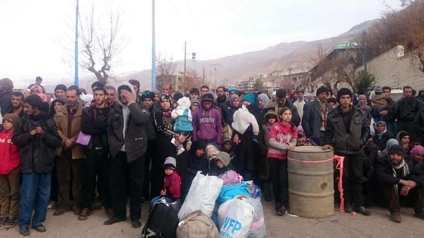 Syrians wait for the arrival of an aid convoy in the besieged town of Madaya