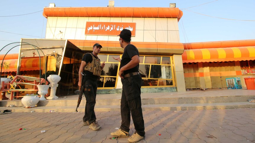 Iraqi security forces inspect the site of a bomb attack in a restaurant.