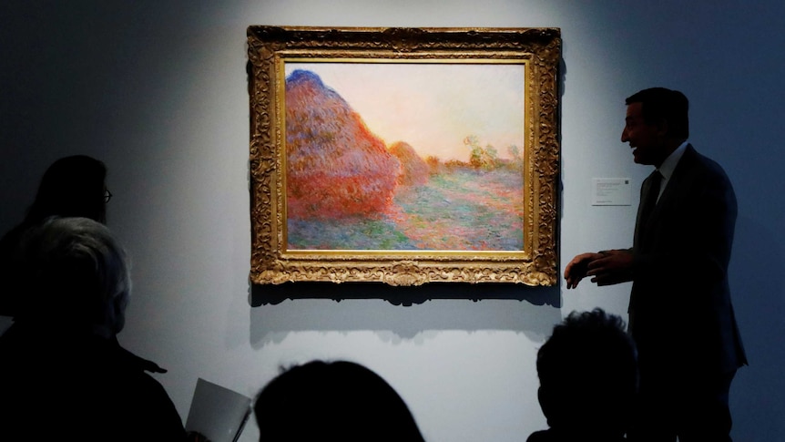 Silhouettes of people can be seen around the gold-framed impressionist painting, which hangs on a blue wall.