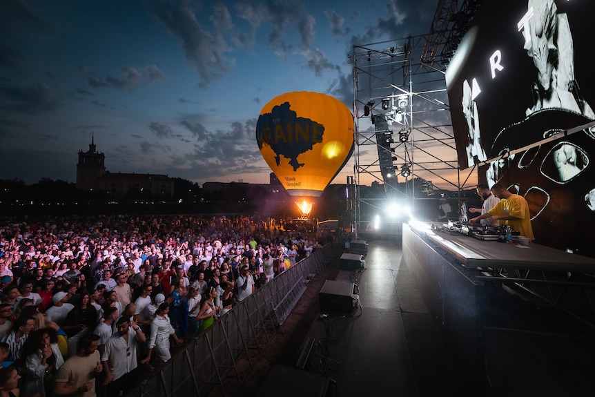 Performers DJ on a stage in front on a huge crowd. A giant balloon reads "slava Ukraini"