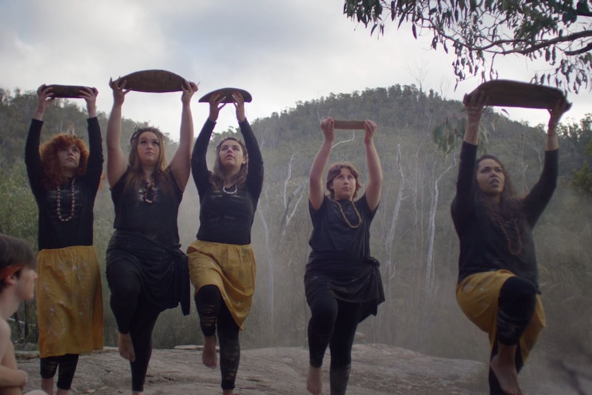 Five girls in traditional aboriginal dress perform a dance.