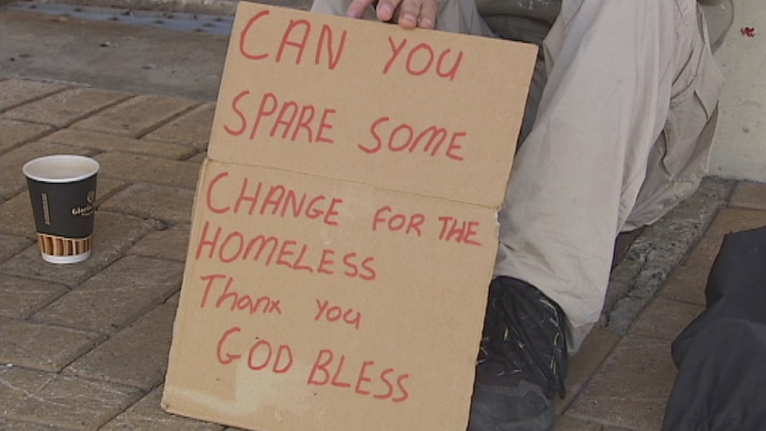 A beggar holds a sign in Fremantle asking for help