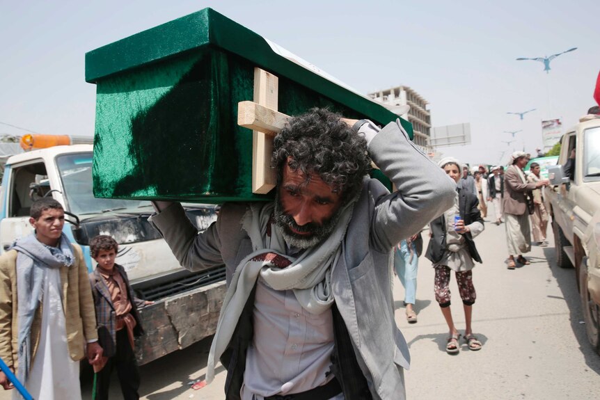 A Yemeni man carries the coffin of a victim